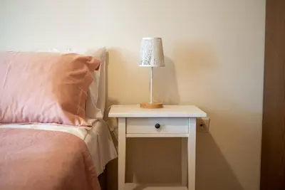 a bed with a table with a lamp on it at Manos Home in Spiliá