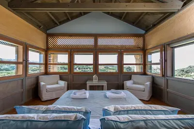 a room with a bed and two chairs and windows at Villa Catani in Kalamaki Chanion
