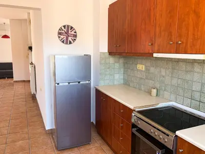 a kitchen with a stainless steel refrigerator and wooden cabinets at CENTRAL HUGE LUXURY APARTMENT and FREE PARKING in Chania Town