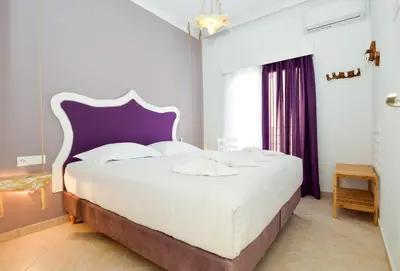 a bedroom with a large white bed with a purple headboard at Rubini City Apartment in Chania Town