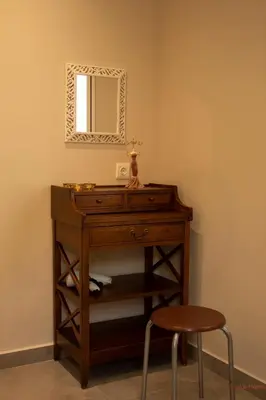 a wooden dresser with a mirror and a stool at Tabak home Sea side apartment in Chania Town