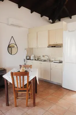 a kitchen with a table and chairs and a white refrigerator at Lefteris Rooms in Kámbos
