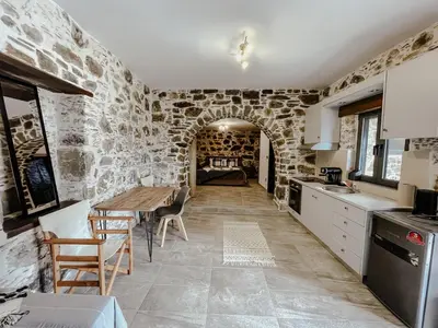 a kitchen with a wooden table and a stone wall at Lefteris Rooms in Kámbos