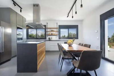 a kitchen with a wooden table and chairs in a kitchen at Elixsea Villa - Unlimited view of the Blue sea in Kounoupidhianá