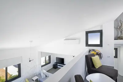 a living room with white walls and a staircase at Elixsea Villa - Unlimited view of the Blue sea in Kounoupidhianá