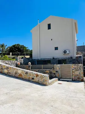 a building with a stone retaining wall and a garage at Pink Sand-Studio in Agios Padeleimon