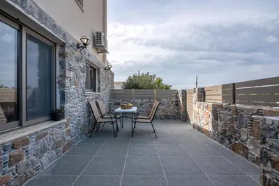 a patio with a table and chairs on a stone wall at Pink Sand-Studio in Agios Padeleimon