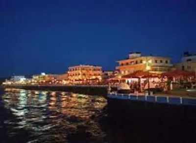 a group of buildings on the water at night at CASA di LIMONI in Kissamos