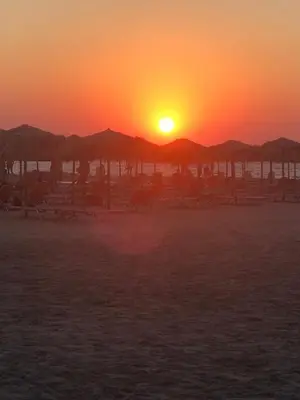 a sunset on a beach with umbrellas and the ocean at CASA di LIMONI in Kissamos