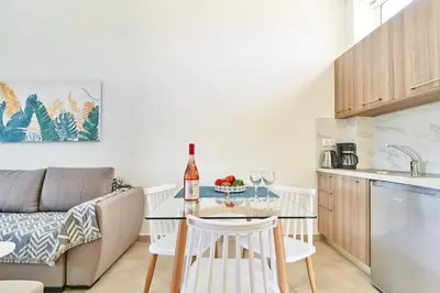 a kitchen and living room with a table with a bottle of wine at Bella Apartment in Kissamos
