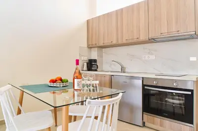 a kitchen with a glass table and white chairs at Bella Apartment in Kissamos