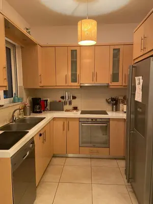a kitchen with wooden cabinets and a stainless steel refrigerator at Villa Harriet Maria with pool and ocean view Kolimbari, Chania in Kolymvari