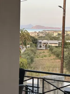 a balcony with a view of a house and the ocean at Villa Harriet Maria with pool and ocean view Kolimbari, Chania in Kolymvari