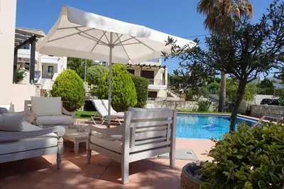 a patio with an umbrella and chairs and a pool at Villa Harriet Maria with pool and ocean view Kolimbari, Chania in Kolymvari