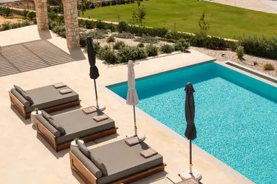two lounge chairs with umbrellas next to a swimming pool at Tholaria Villa in Chania Town