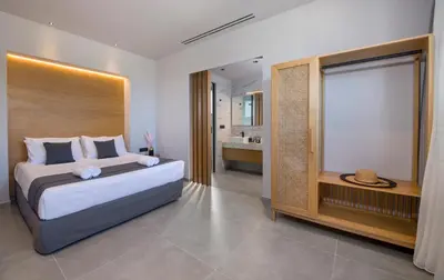 a bedroom with a large bed and a bathroom at Xenias Luxury Villas Kalathas in Kalathas