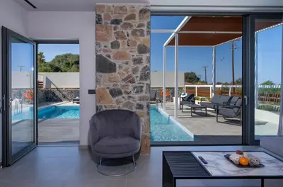 a living room with a chair and a pool at Xenias Luxury Villas Kalathas in Kalathas