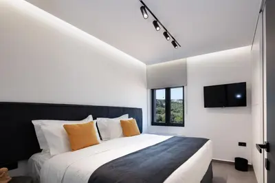 a bedroom with a large bed and a tv at Horizon Luxury Villa in Chania Town