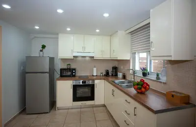 a kitchen with white cabinets and a sink and a refrigerator at Unique Apartment in Chania Town