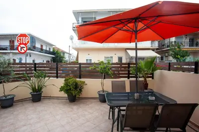 a patio with a table and a red umbrella at Unique Apartment in Chania Town