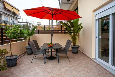 a table and chairs with a red umbrella on a balcony at Unique Apartment in Chania Town
