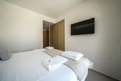 a bedroom with a white bed with a television on the wall at Villa Olira in Alikianós
