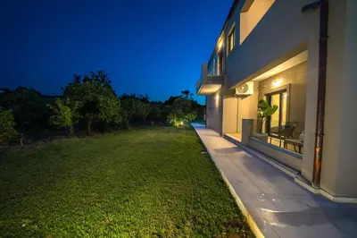 a house with a lawn next to a building at Villa Florentina at Chania Suburbs With Private Pool and BBQ in Alikianós