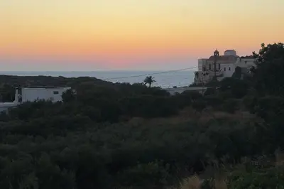 a building on a hill with the ocean in the background at Thea Studio in Agios Padeleimon