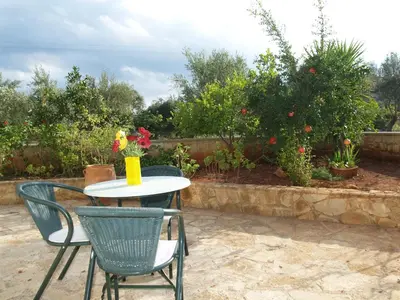 a table and chairs with flowers on a patio at Irida Apartments -EX BLAZIS HOUSE in Almirida