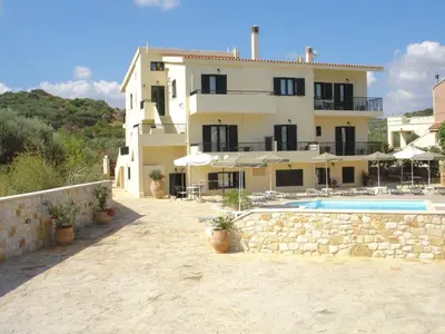 a large house with a swimming pool in front of it at Irida Apartments -EX BLAZIS HOUSE in Almirida
