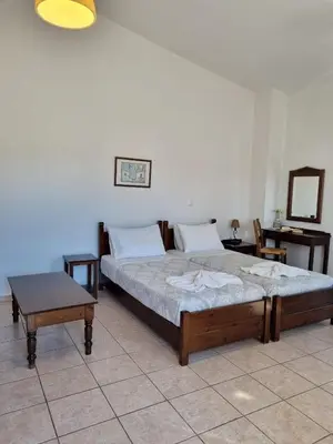 a bedroom with two beds and a table and a mirror at Irida Apartments -EX BLAZIS HOUSE in Almirida