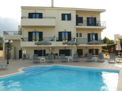 a villa with a swimming pool in front of a building at Irida Apartments -EX BLAZIS HOUSE in Almirida
