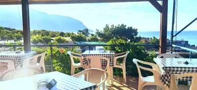 a restaurant with tables and chairs and a view of the ocean at Paradise in Agia Roumeli