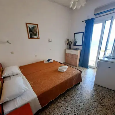 a bedroom with a large bed and a large window at Paradise in Agia Roumeli