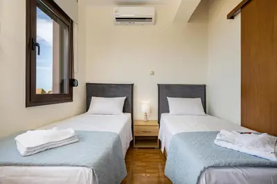 two twin beds in a room with a window at Villa Mari Chania, with private ecologic pool and amazing view! in Chania Town