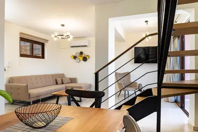 a living room with a couch and a staircase at Villa Mari Chania, with private ecologic pool and amazing view! in Chania Town