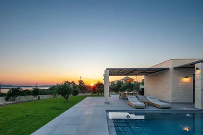 a villa with a swimming pool and a sunset at Ikritis Villas in Chorafakia