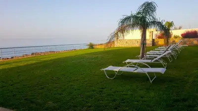 a row of lounge chairs sitting in a grass field at Kritamos Beach Apartments in Frangokastello