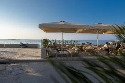 a group of people sitting at tables under umbrellas on the beach at PLUS 2! in Chania Town