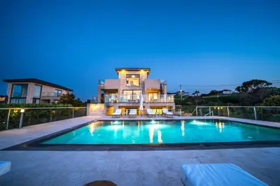 a house with a swimming pool in front of a house at Villa Poseidon One - Sunset & Sea Front Villa in Chorafakia