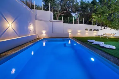 a swimming pool in a backyard at night with lights at El Platanias in Chania Town