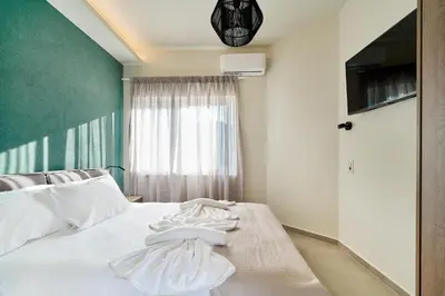 a bedroom with a bed with white sheets and a window at El Platanias in Chania Town