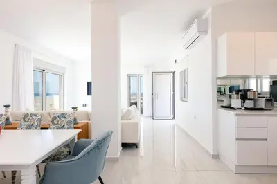 a white kitchen and living room with a table and chairs at Vista Residence in Chania Town