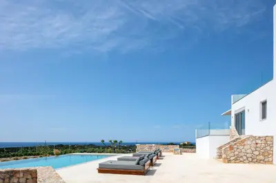 a pool with chaise lounge chairs next to a building at Vista Residence in Chania Town