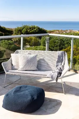 a white couch with pillows on a balcony with the ocean at Magnifique villa avec piscine au bord de mer in Chorafakia