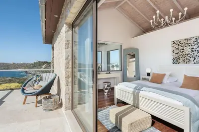 a bedroom with a bed and a balcony at Magnifique villa avec piscine au bord de mer in Chorafakia