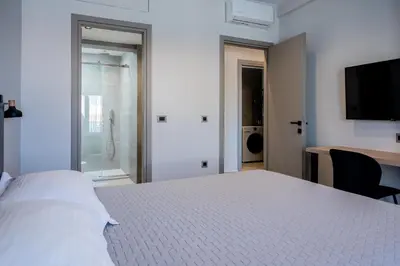 a bedroom with a white bed and a sliding glass door at Yiannis Deluxe Apartment in Chania Town