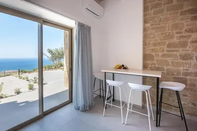 a room with a table and chairs and a view of the ocean at Alma Natura Villas Falasarna- Avgerinos Villa in Falasarna