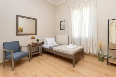 a bedroom with a bed and a chair and a mirror at Πλήρως ανακαινισμένη μονοκατοικία. in Chania Town