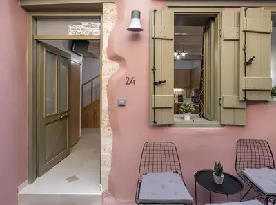 a pink house with a table and chairs next to a door at Vaggelis house in Chania Town